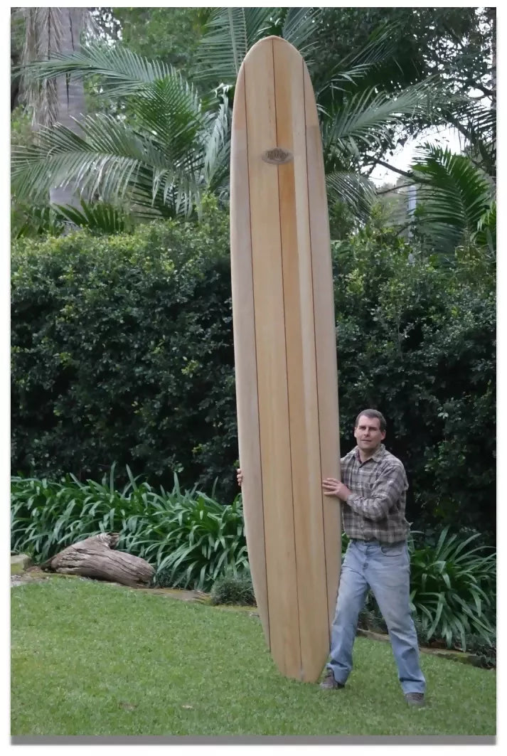 Full length 12ft Riley Solid Balsa Classic Malibu surfboard standing outdoors