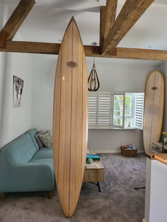 Full view of the Riley foam core balsa Hawaiian Gun surfboard standing indoors