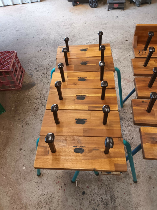 A row of handmade timber two-spike hat and coat racks with shelves in Noah's Creations workshop.