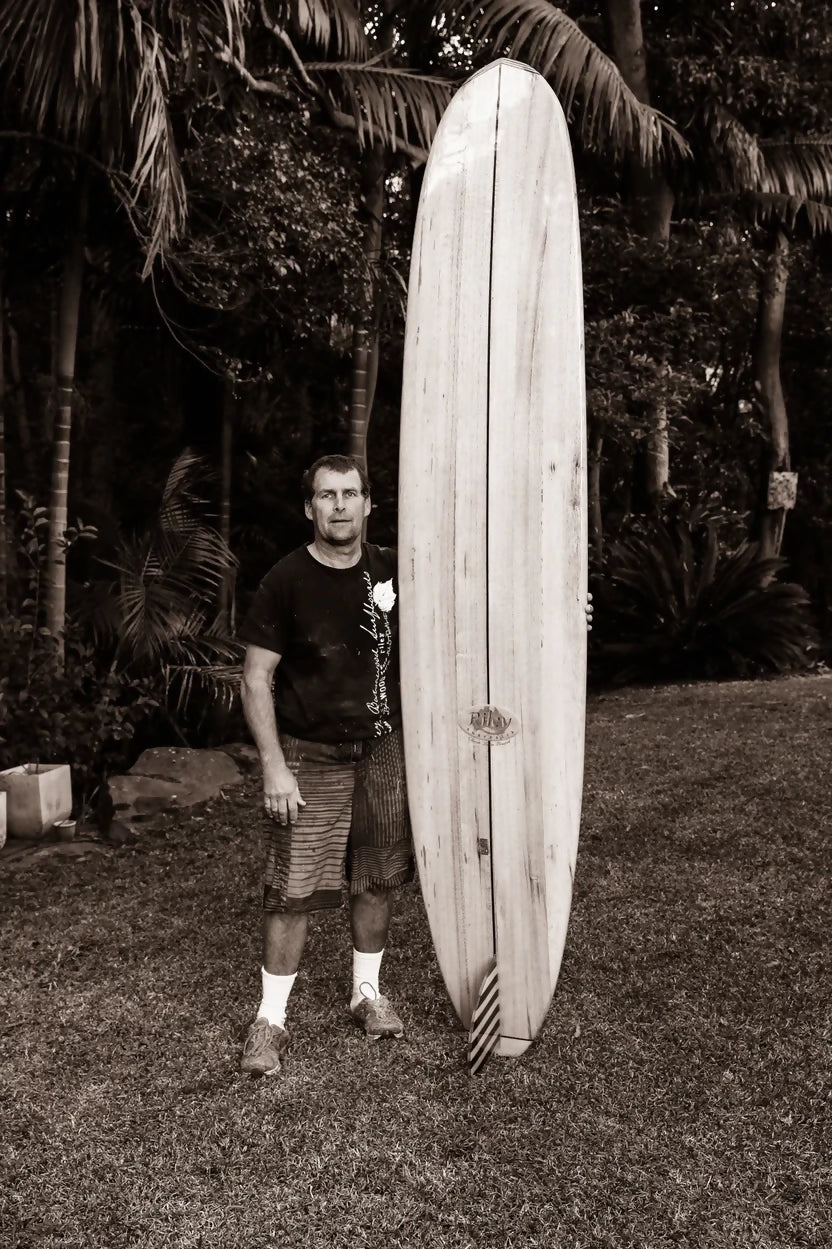 Mark Riley with a Solid Balsa Classic Malibu surfboard in black and white
