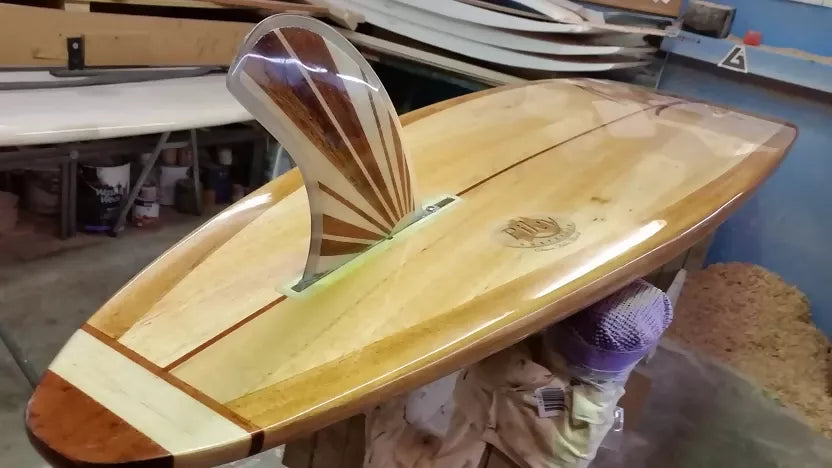 Riley solid balsa Hawaiian Gun surfboard resting on a stand in the workshop