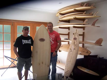 Surfer standing beside a Riley balsa Fish surfboard on the beach