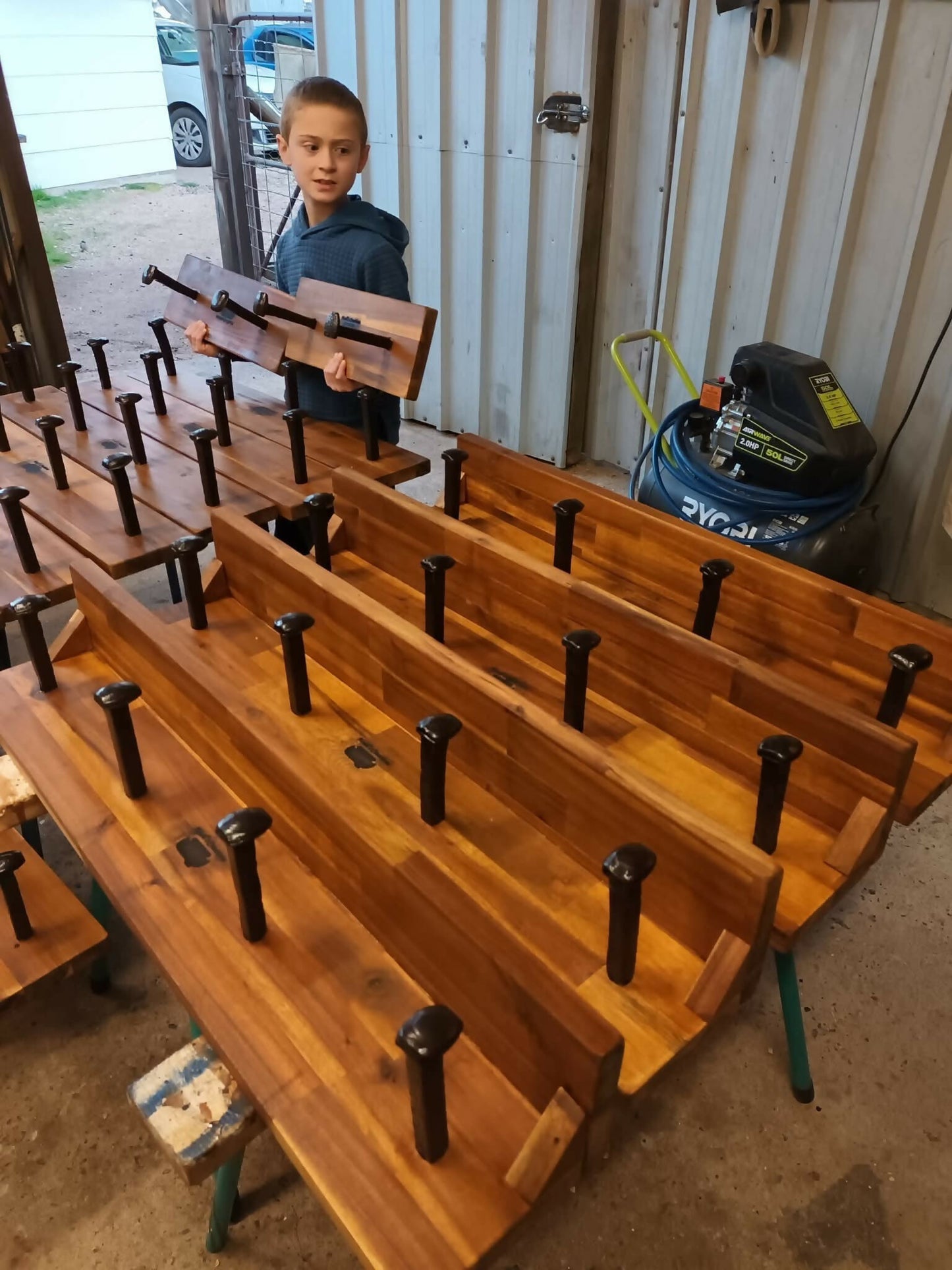 Young maker applying the finish to a handmade timber 4 Spike Hat & Coat Rack by Noah's Creations.