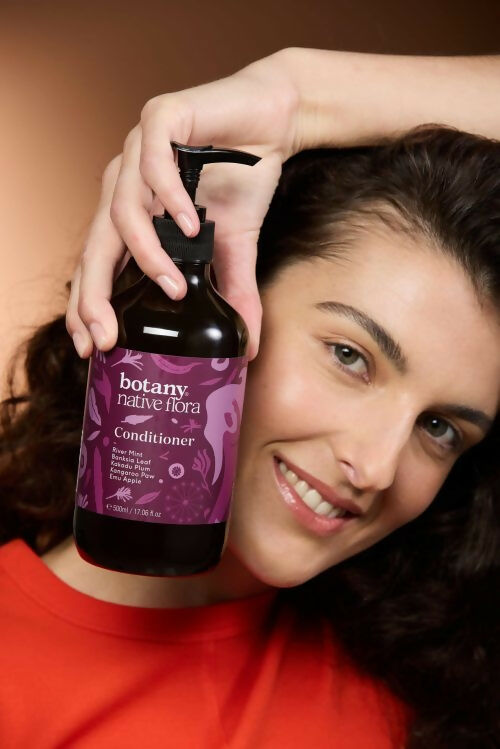 Woman holding Botany Native Flora Conditioner 500ml Australian made hair care