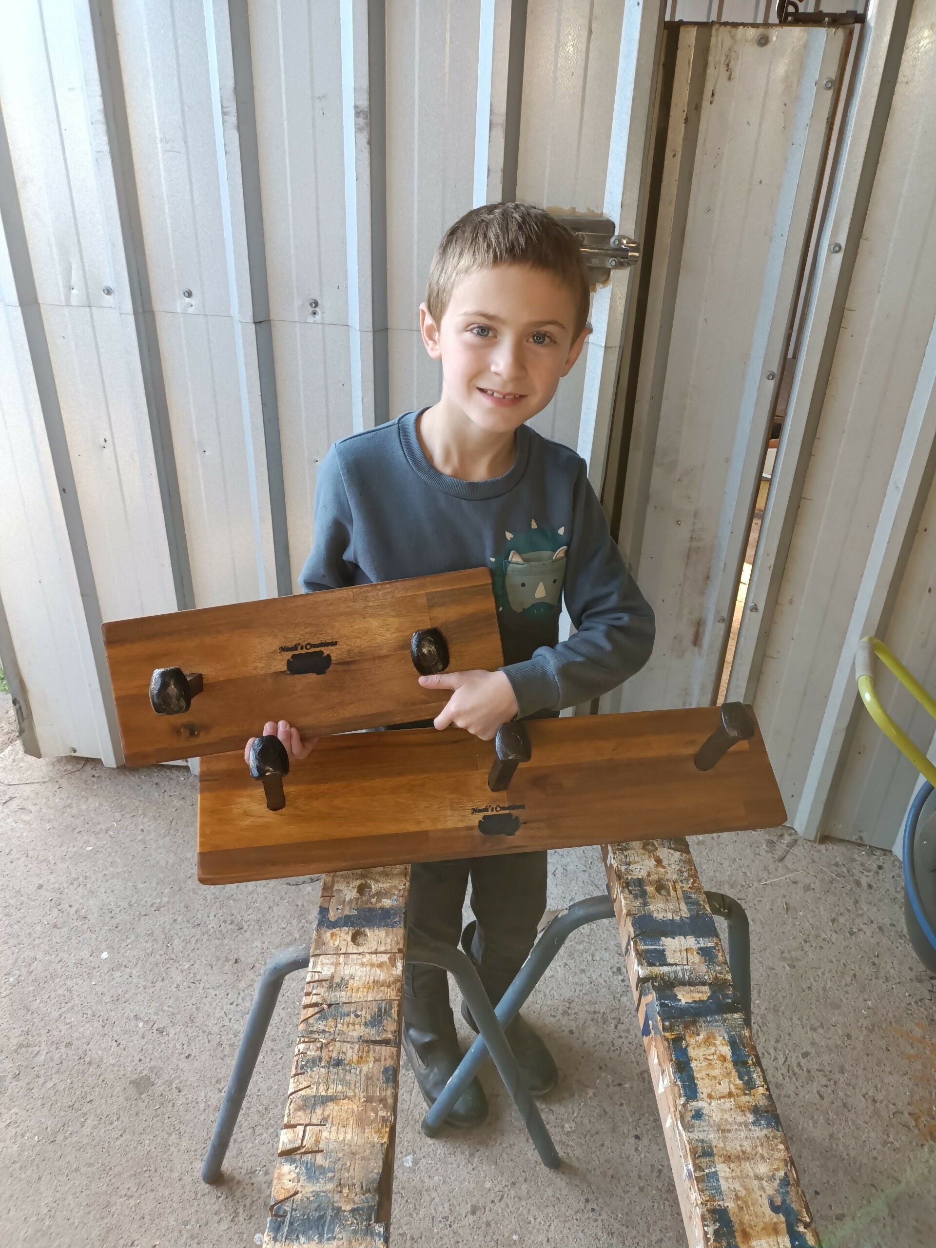 Young maker holding a handmade timber 3 Spike Hat & Coat Rack by Noah's Creations.
