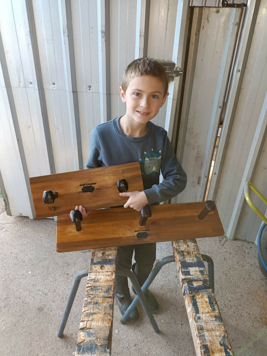 Young maker holding a handmade timber 3 Spike Hat & Coat Rack by Noah's Creations.