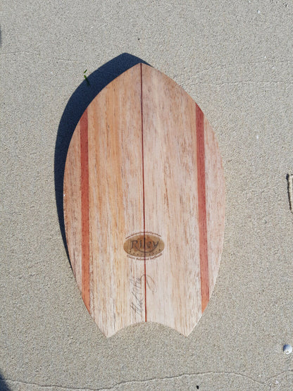 Top view of a handcrafted solid balsa bodysurfing handboard on beach sand