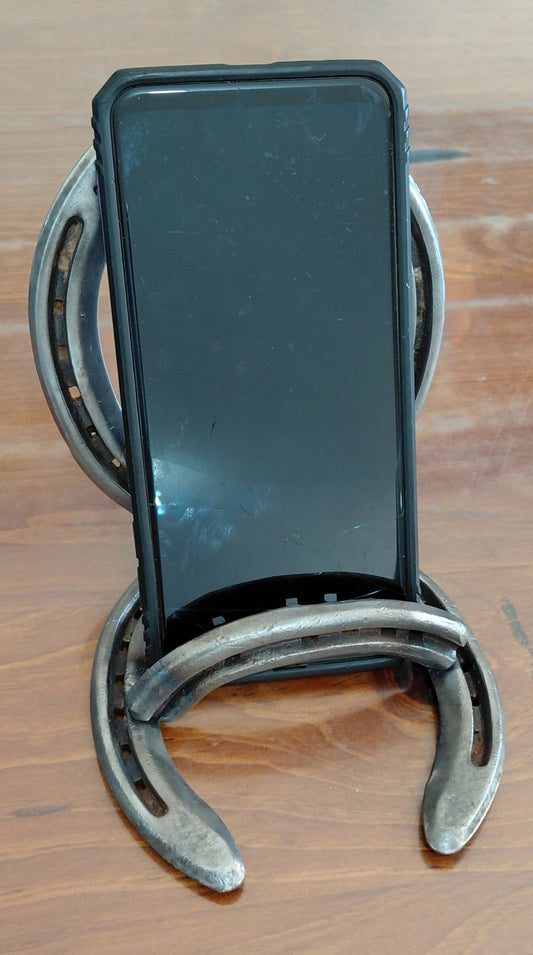 Handmade horseshoe mobile phone and tablet cradle by Noah's Creations holding a smartphone.
